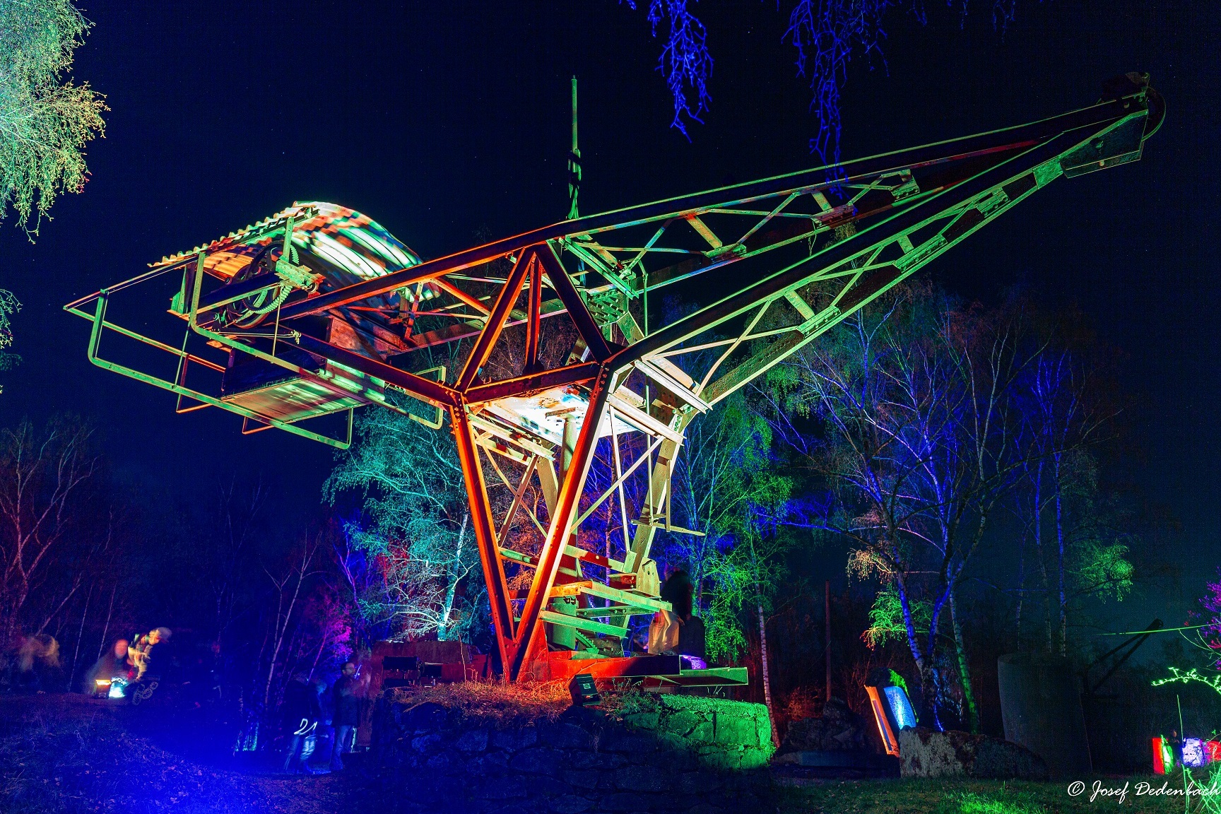 Historischer Kran im dunkeln der von bunten lichtern angeleuchtet wird
