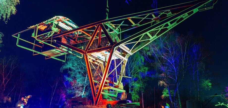 Historischer Kran im dunkeln der von bunten lichtern angeleuchtet wird