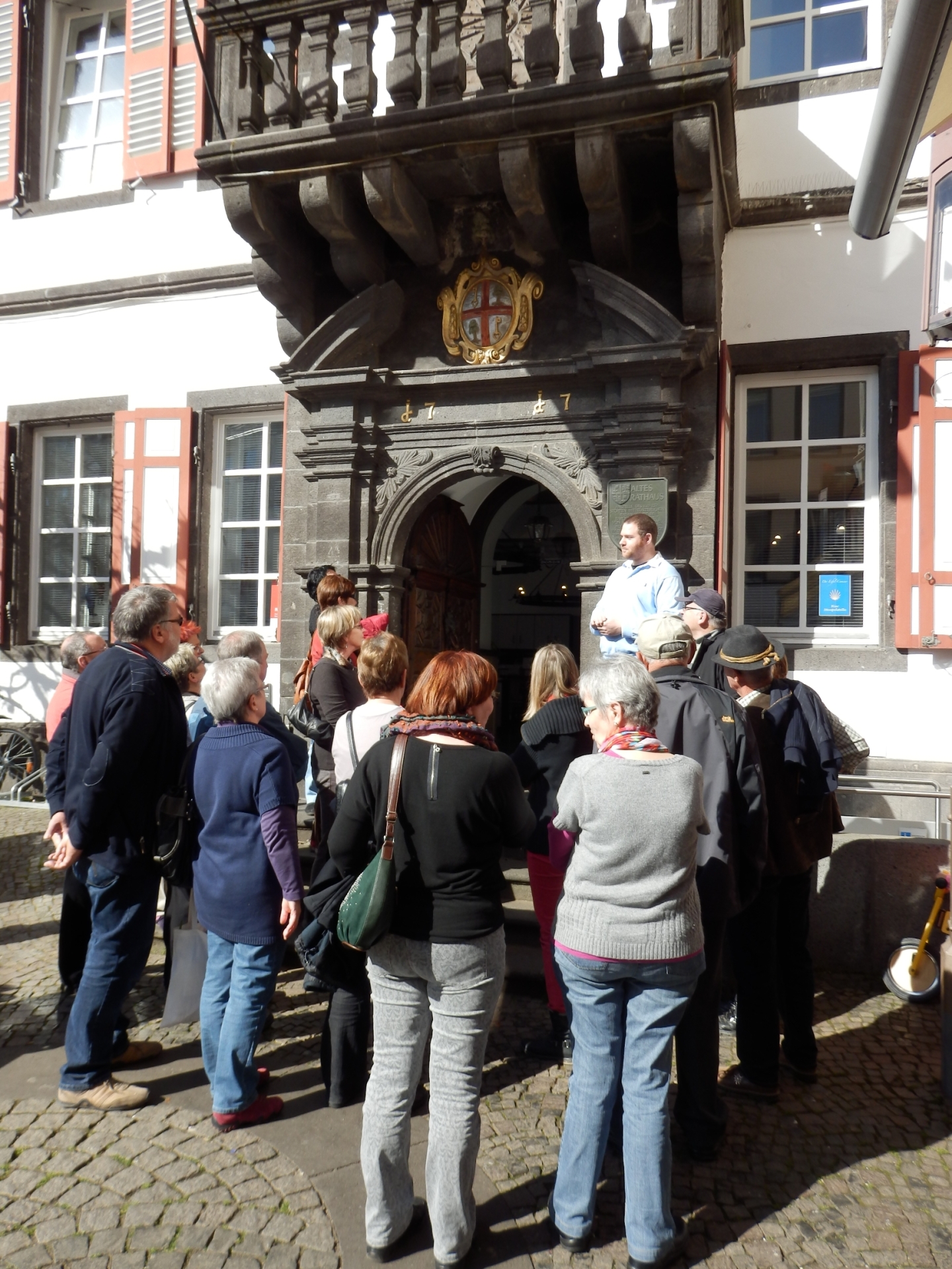 Menschen stehen vor dem Alten Rathaus und hören einem Sprecher zu