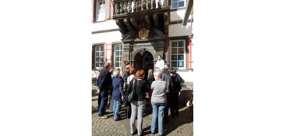 Die offenen Themen-Führungen laden im Herbst dazu ein, Mayen aus unterschiedlichen Perspektiven zu entdecken. Menschen stehen vor dem Alten Rathaus und hören einem Sprecher zu