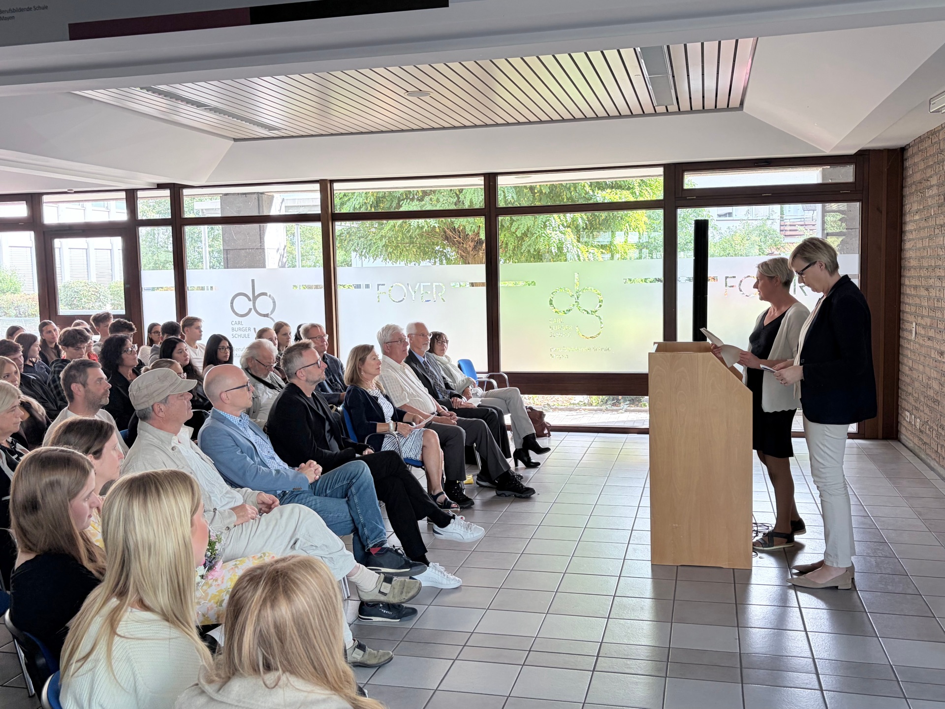 Viele Menschen sitzen auf Stühlen und hören gespannt einem Vortrag zu.