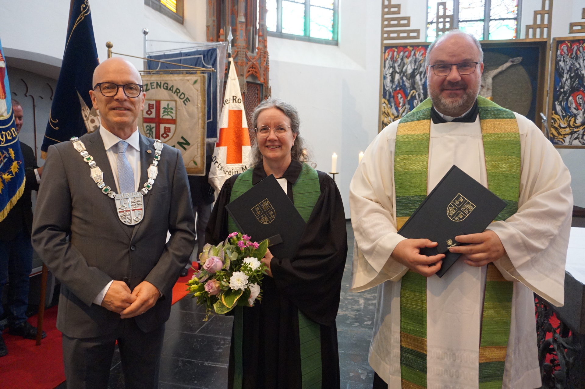 Oberbürgermeister Dirk Meid steht links neben Pfarrerin Metje Steinau und Dekan Jörg Schuh in einer Kirche