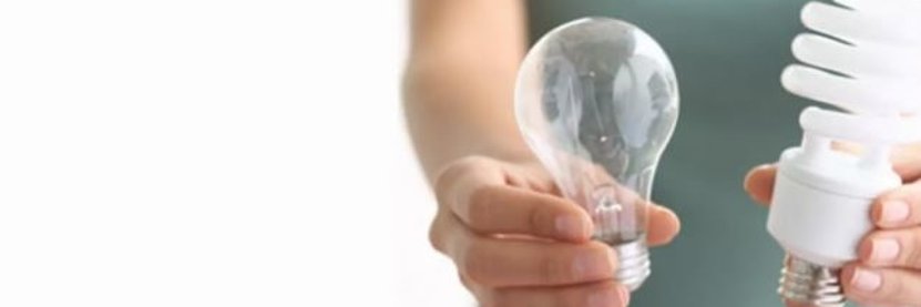 Person hält links eine Glühbirne, rechts eine Energiesparlampe in der Hand