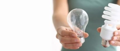 Person hält in der linken Hand eine Glühbirne und in der rechten Hand eine Energiesparlampe