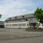 Schulgebäude weiß mit großem Vorplatz