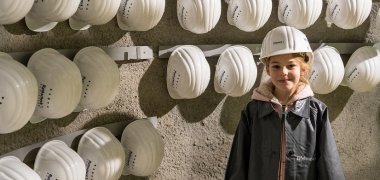 Kind steht bei den Sicherheitshelmen in der Ausstellung Deutsches Schieferbergwerk Kind in der Ausstellung Deutsches Schieferbergwerk