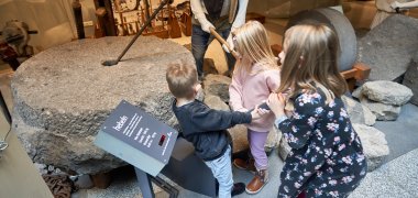 Kinder bearbeiten einen Mühlstein 