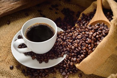 Cafés Eine Tasse Kaffee mit einem Sack Kaffeebohnen daneben