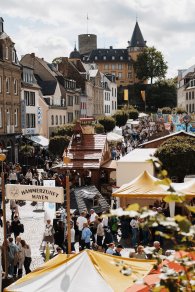 Viele Leute auf dem Markt mit Zelten und Blick auf die Burg