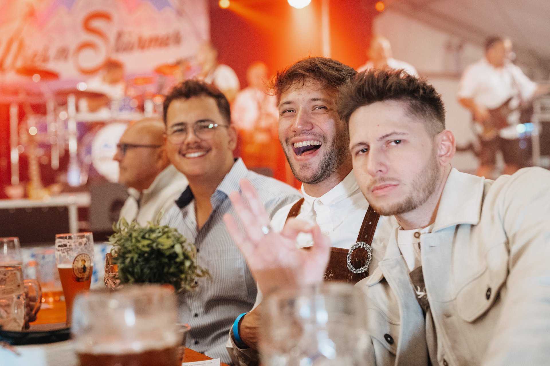 Drei Männer am Tisch mit einem Maß Bier in der Hand