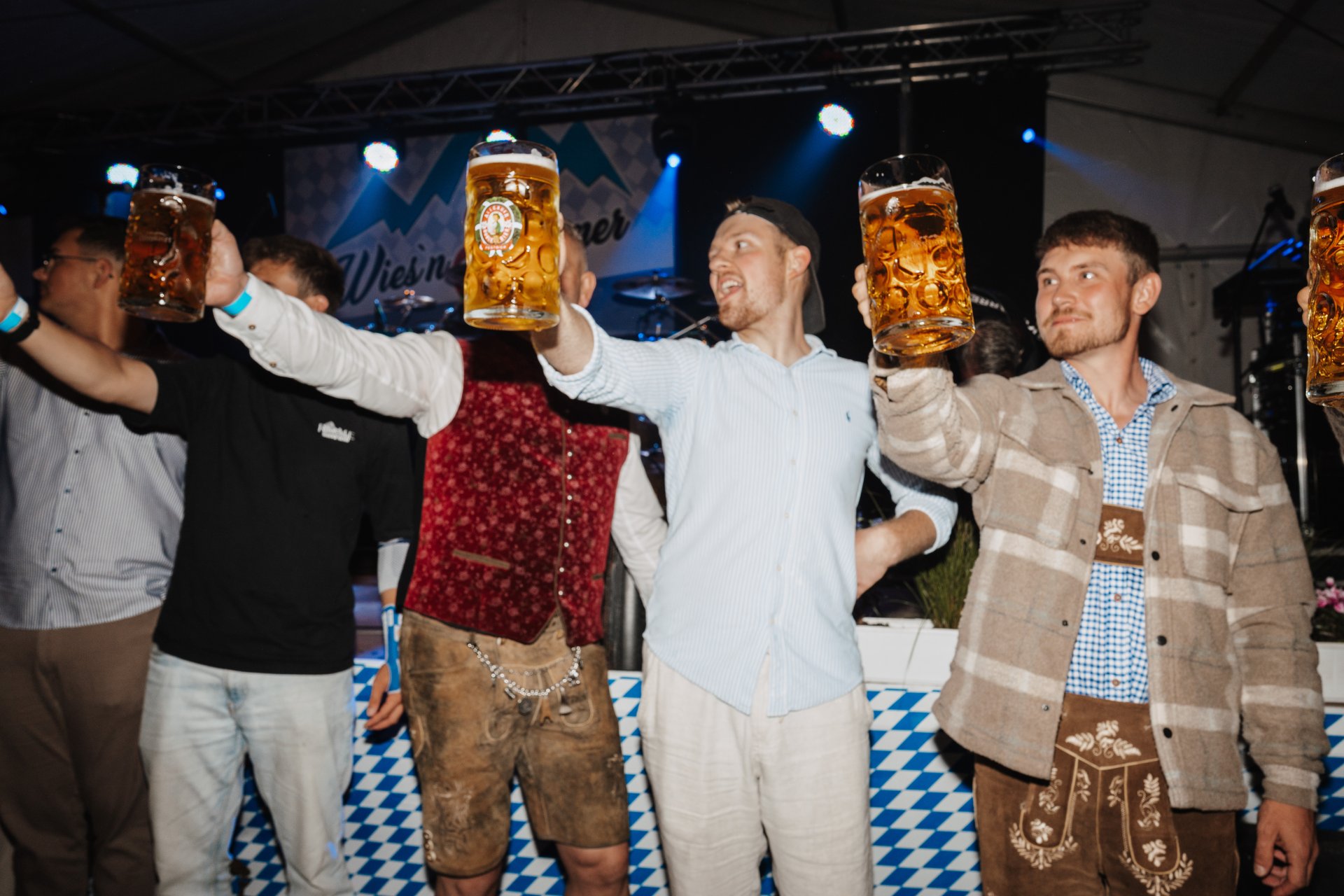 Männer die beim Bierkrug-heben mit einem Maß Bier mitmachen
