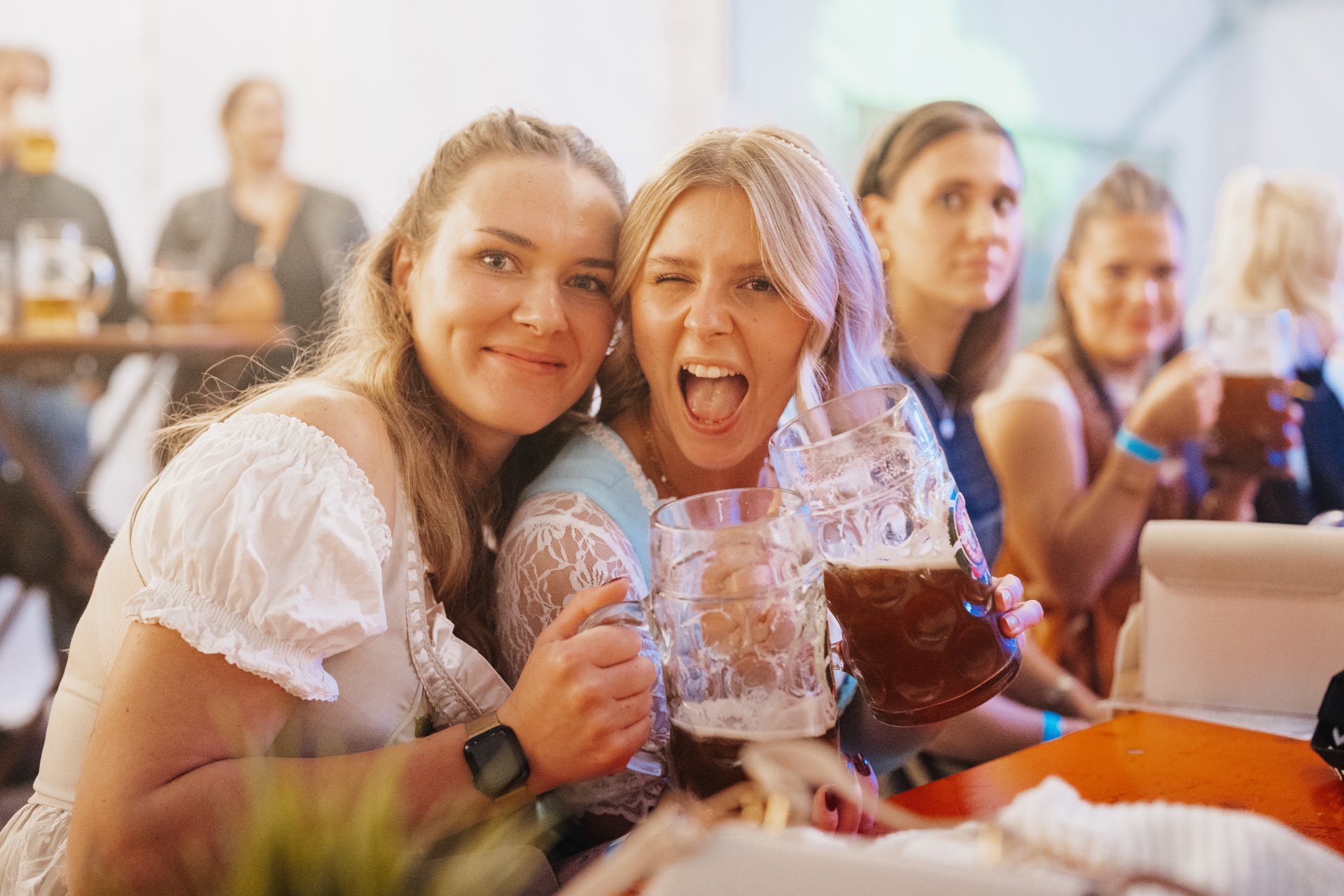 Zwei Frauen mit einem Maß Bier in der Hand, zwinkern in die Kamera